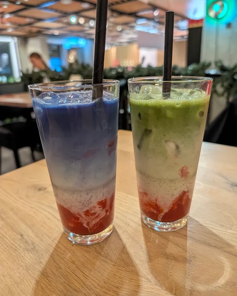 Two tall layered drinks, blue butterfly pea and green matcha over strawberry